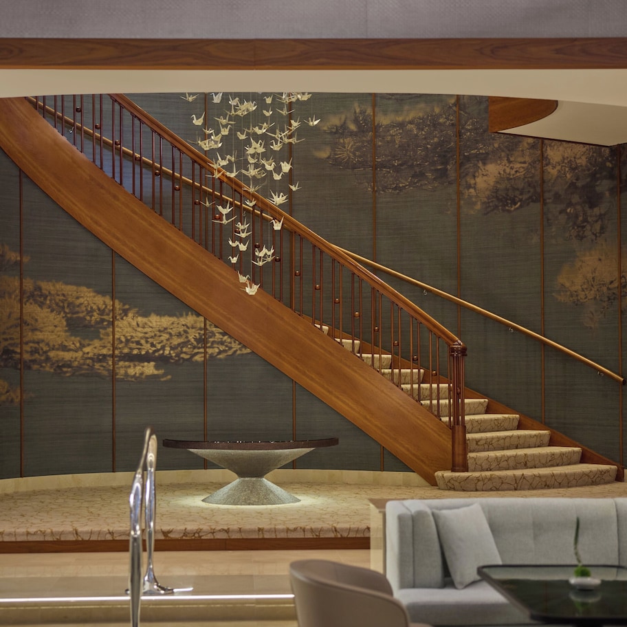 A modern interior with a wooden staircase, a stone table, and a light-colored sofa.