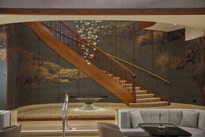 A modern interior with a wooden staircase, a stone table, and a light-colored sofa.