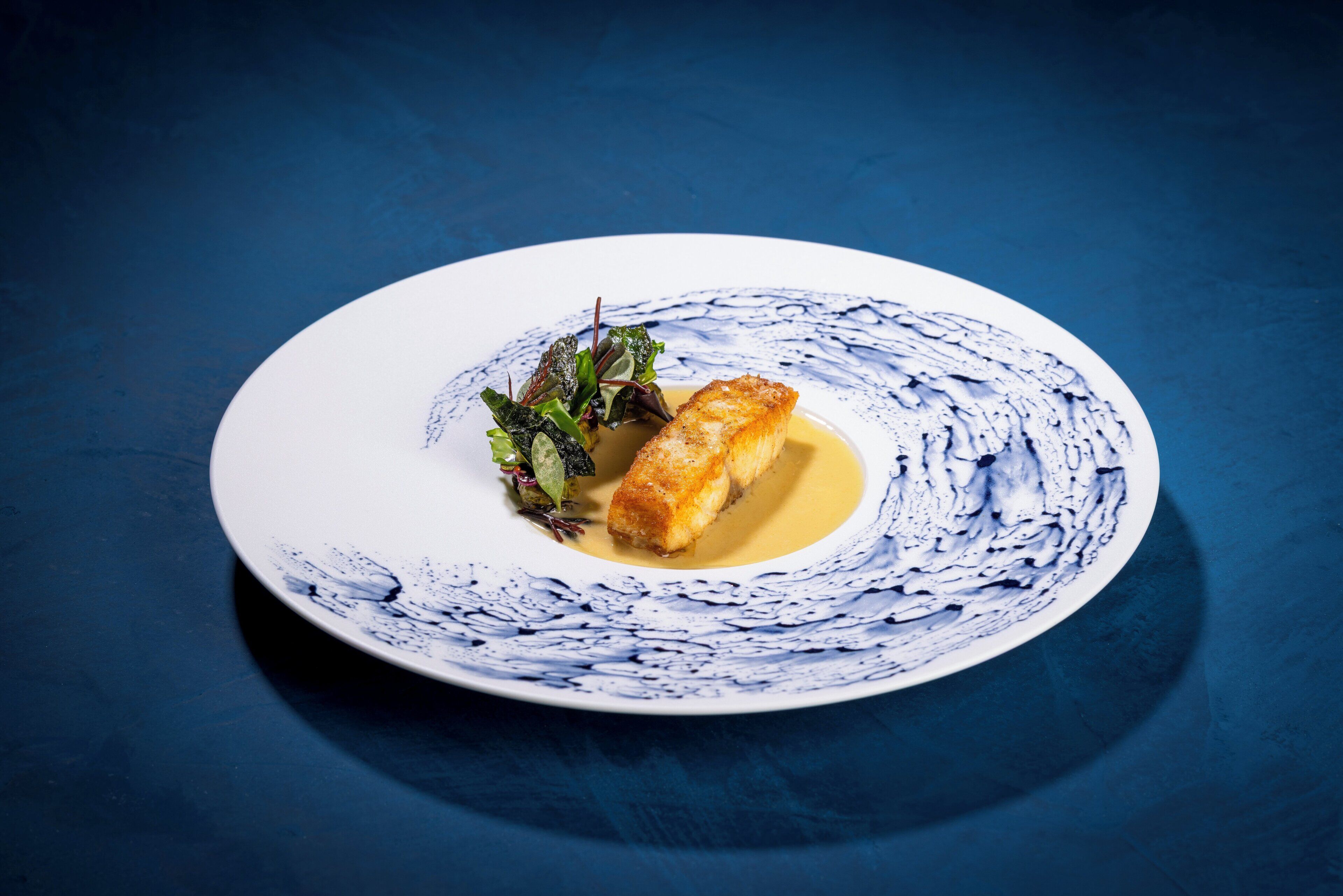 Un plato con un alimento y salsa, sobre un fondo azul.