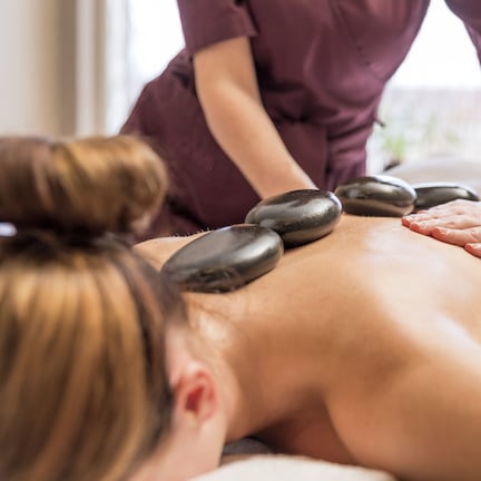 A person receiving a back massage with heated stones.