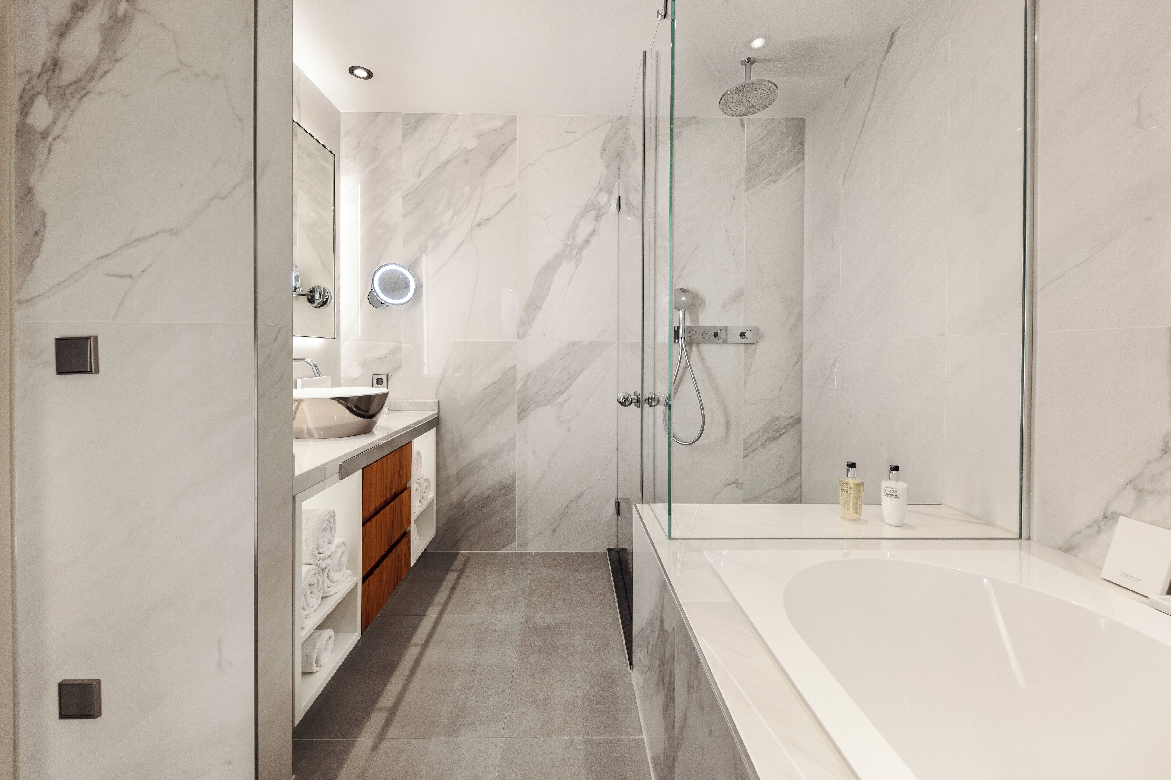 A modern bathroom with a glass-enclosed shower, a large bathtub, and a vanity with a mirror and sink.
