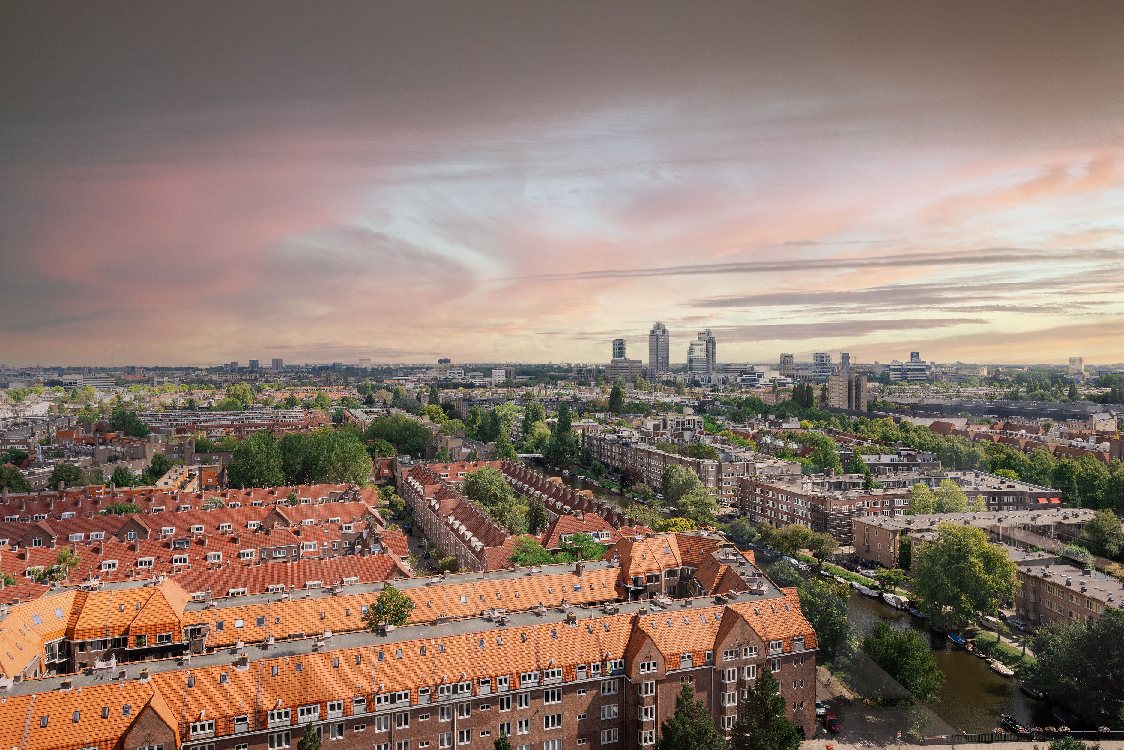 A cityscape with a river, red-roofed buildings, and a distant skyline.