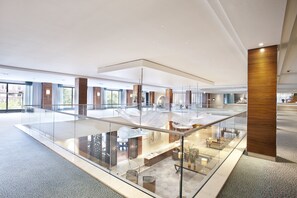A spacious lobby with a glass railing, a reception desk, and a seating area.