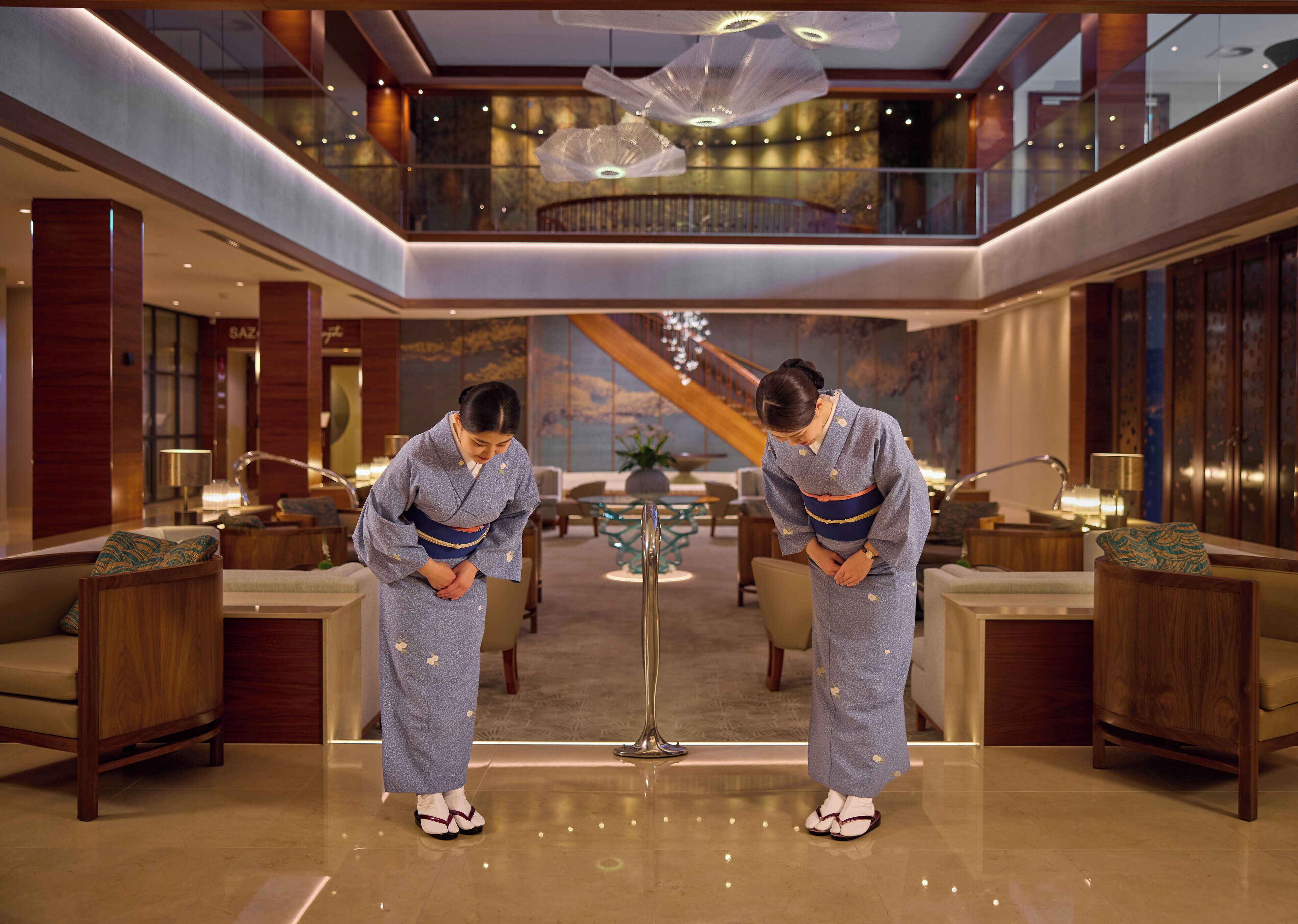 A luxurious lobby with a high ceiling, modern furnishings, and a grand staircase.