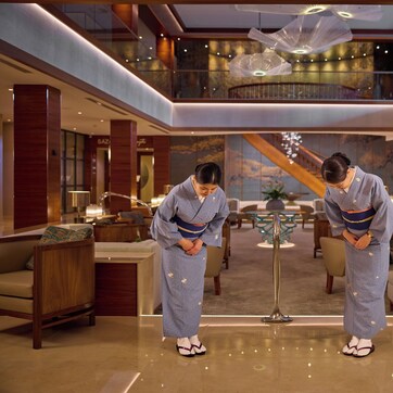 A luxurious lobby with a high ceiling, modern furnishings, and a grand staircase.