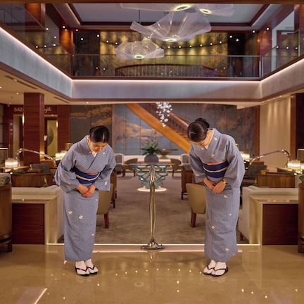 A luxurious lobby with a high ceiling, modern furnishings, and a grand staircase.