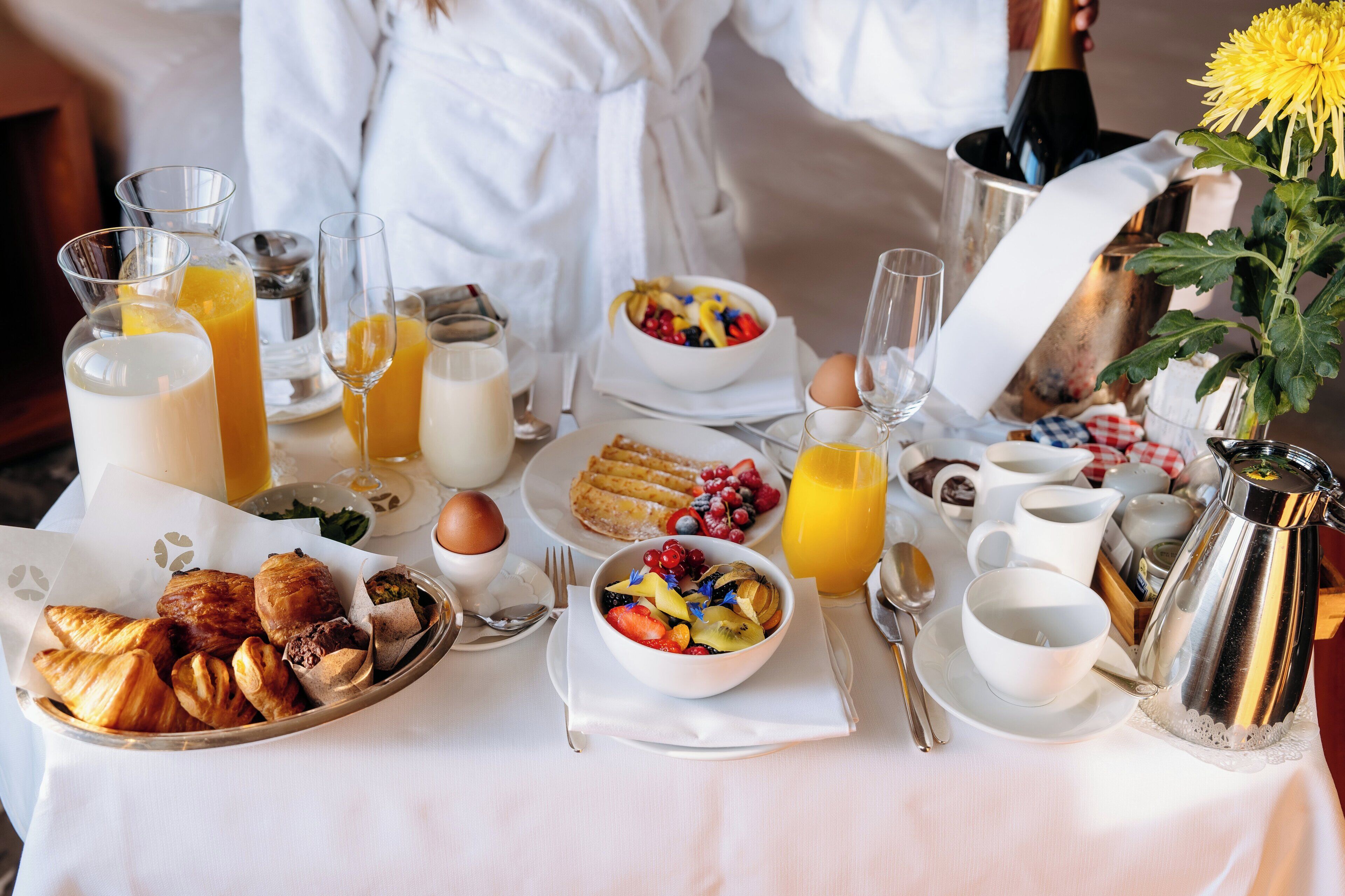 A breakfast table with croissants, fruits, and beverages.