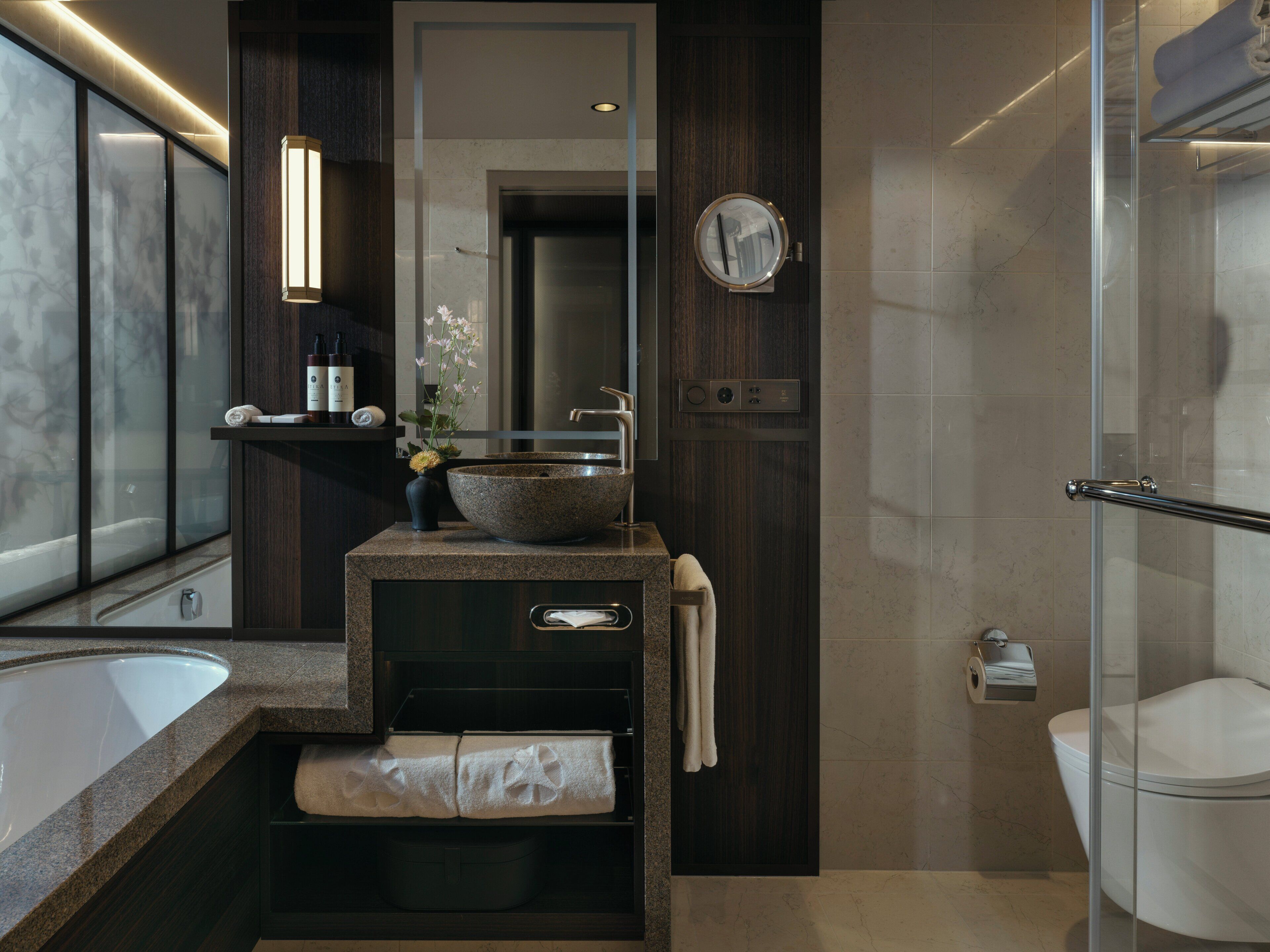 Ein modernes Badezimmer mit einem großen Waschbecken, einem Spiegel und einer Duschkabine aus Glas.