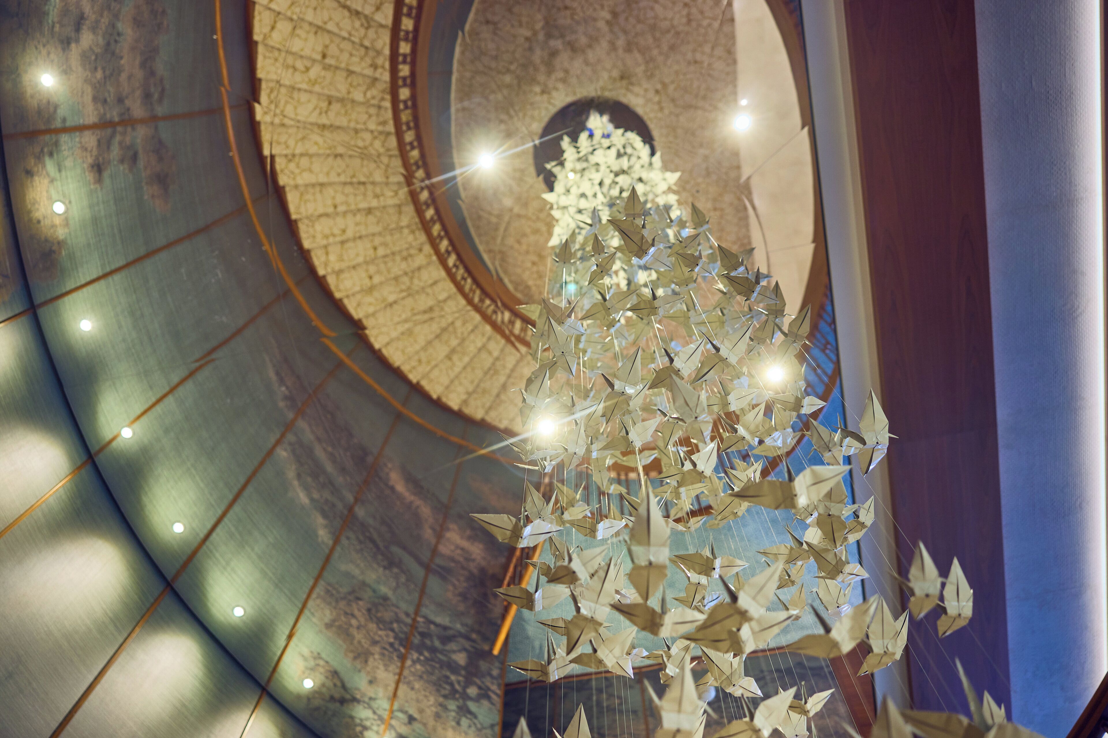 Un escalier en colimaçon surmonté d’un lustre fait de fleurs en papier.