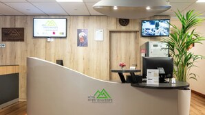 Una recepción de hotel con un logotipo, una pantalla de televisión, un reloj y una planta.