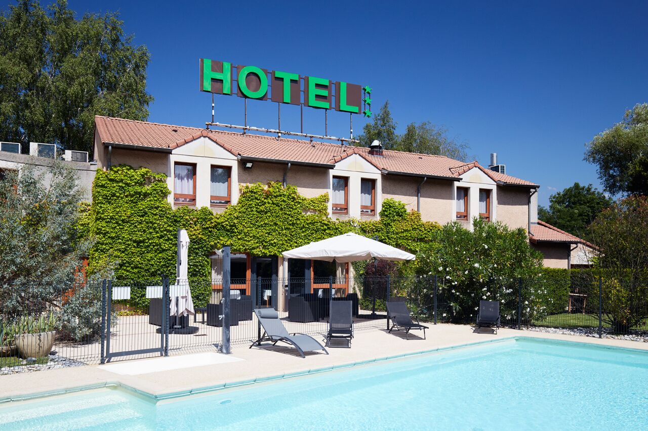 Un hôtel doté d’une piscine, d’un espace extérieur aménagé et d’une enseigne indiquant « HÔTEL ».