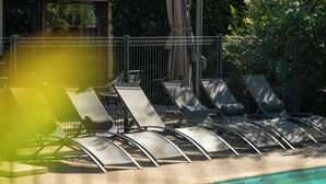 Un área junto a la piscina con sillas de descanso y una valla.