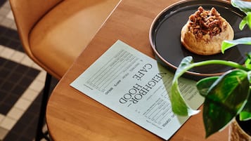 Une table en bois avec un menu, une assiette contenant une pâtisserie, une tasse de café et une chaise.