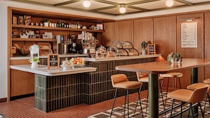 Un café doté d’un comptoir en bois, de tabourets, d’un tableau affichant le menu et présentant divers plats.