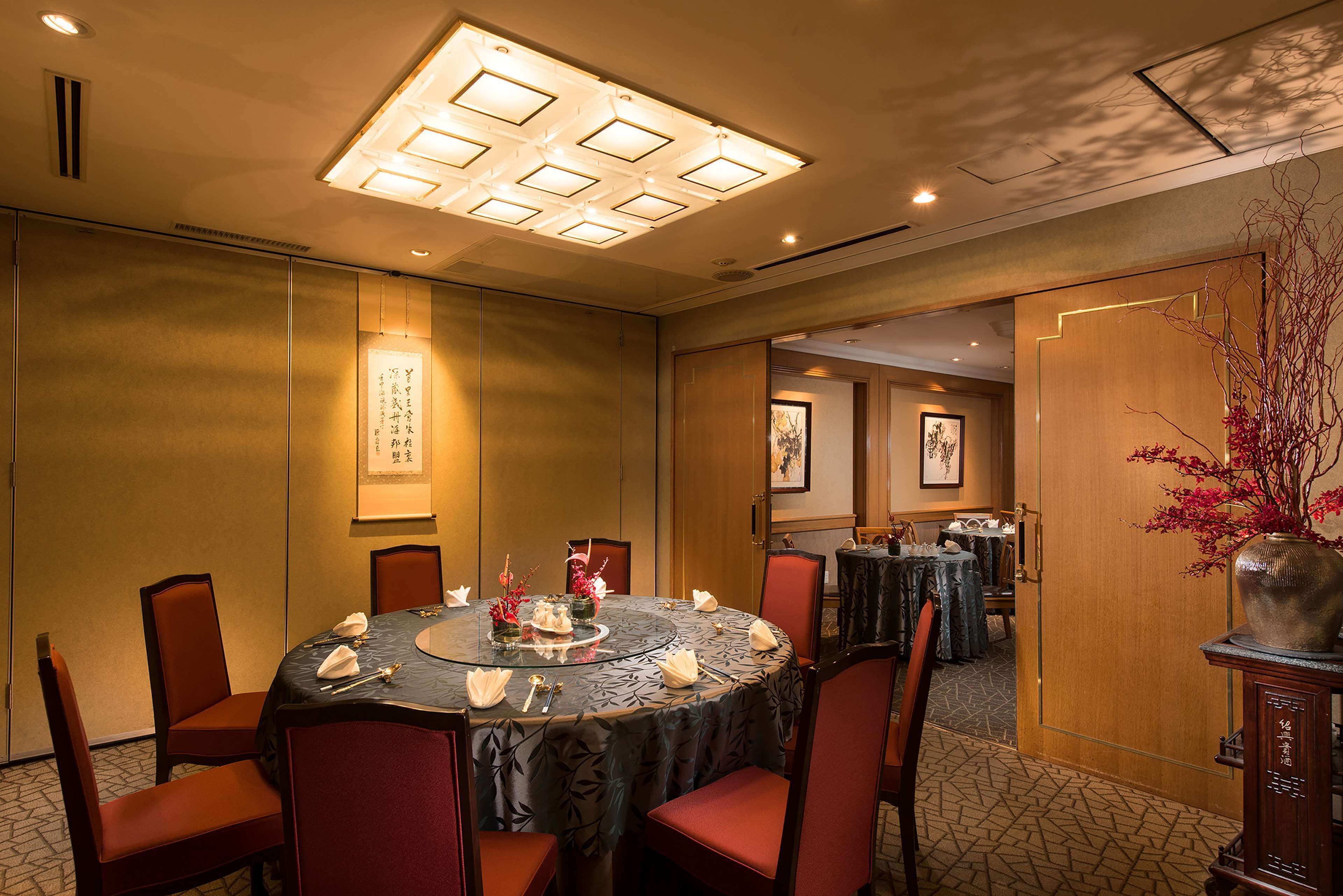 A conference room with a round table, red chairs, and a ceiling light fixture.