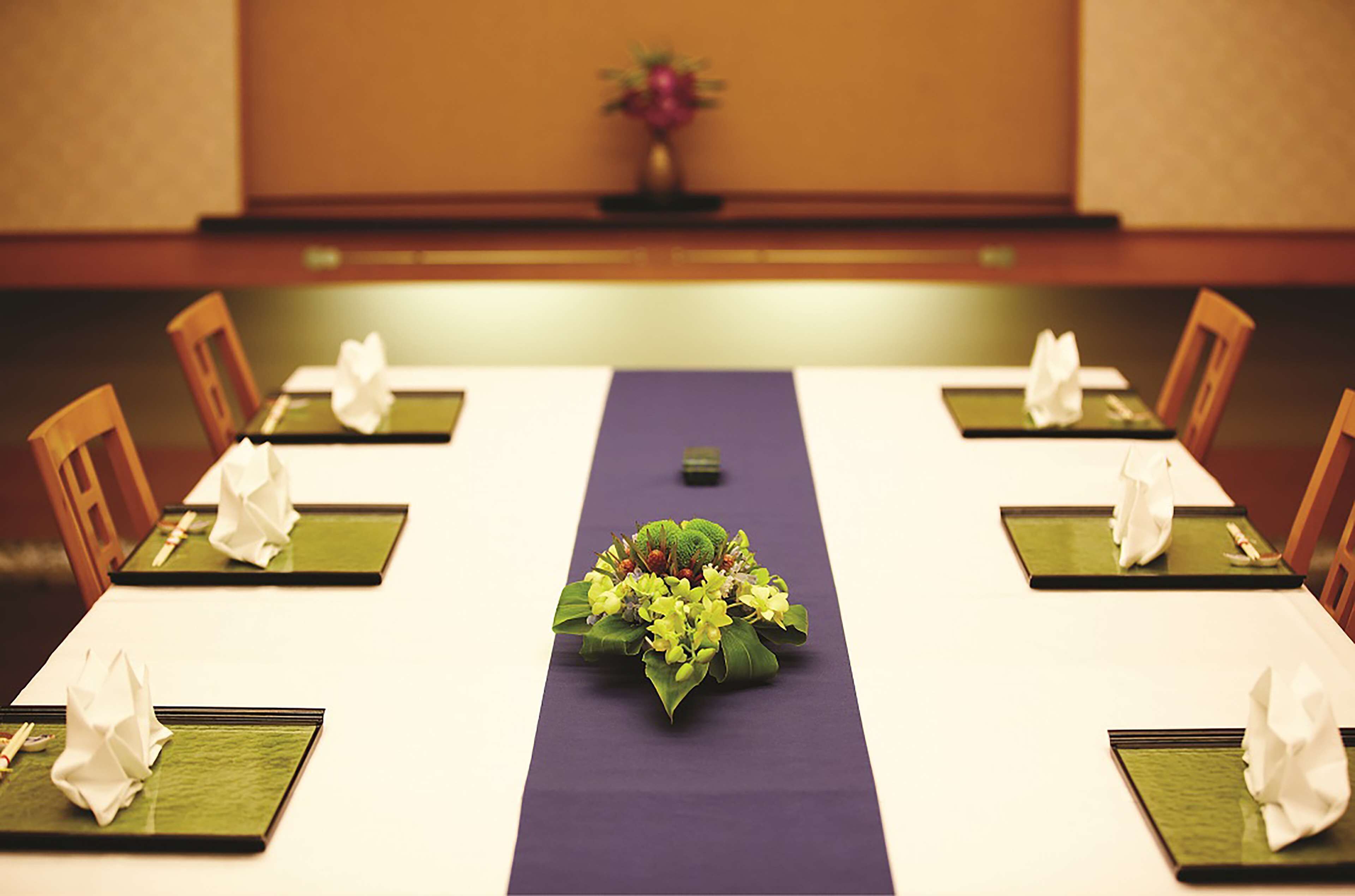 A conference table with green placemats, white napkins, and a purple runner.