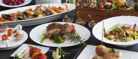 Variedad de platos emplatados con mariscos, vegetales y carnes, dispuestos sobre una mesa.
