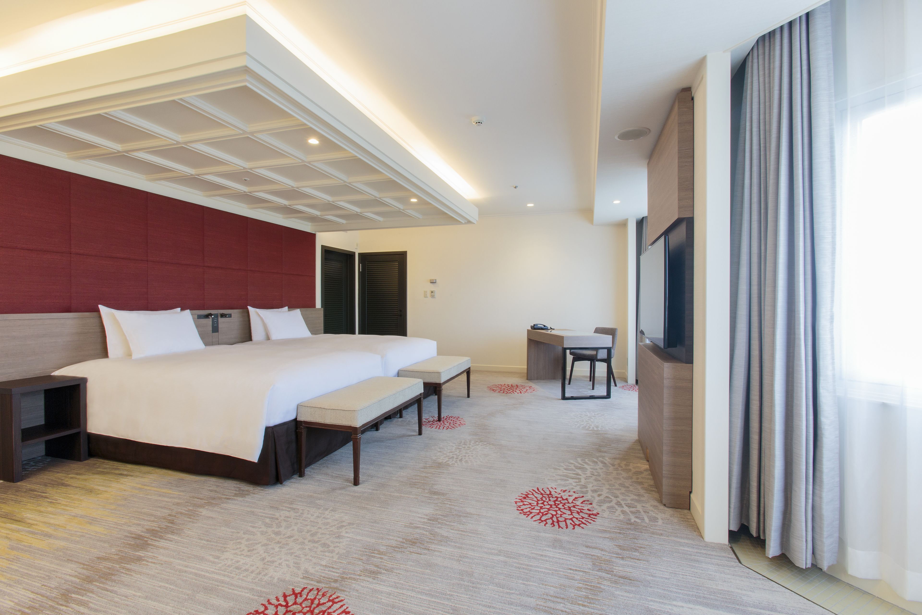 A modern hotel room with a large bed, a desk, and a TV.