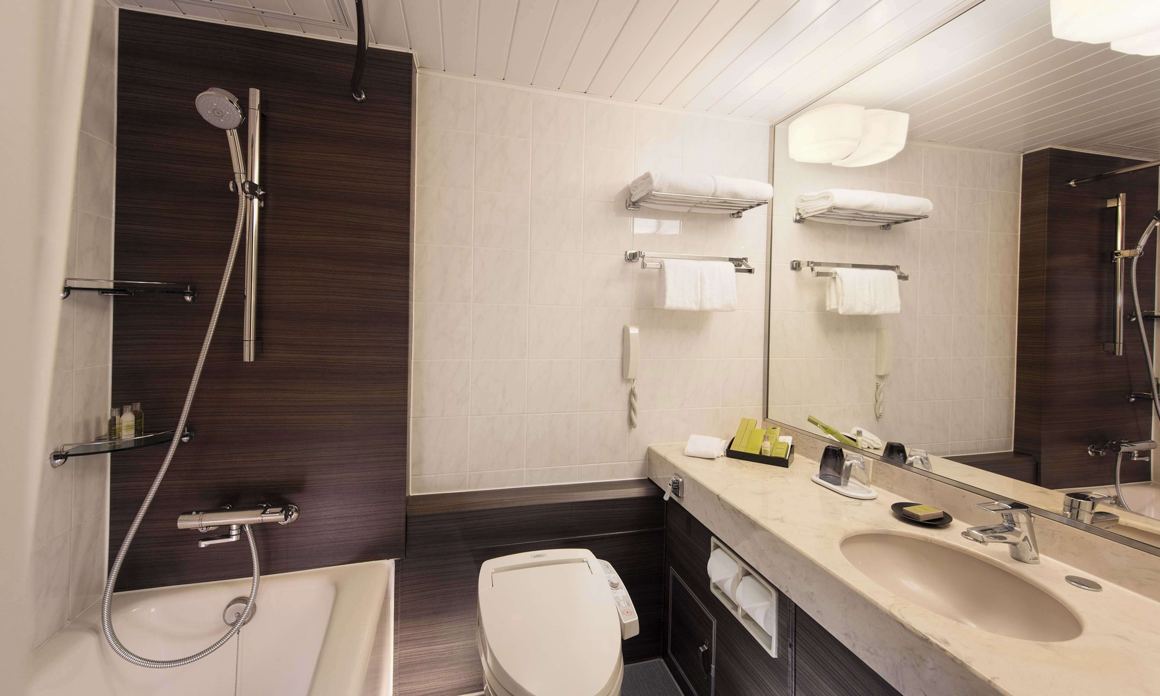 A modern bathroom with a shower, toilet, sink, and a large mirror.