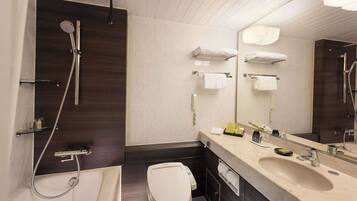 A modern bathroom with a shower, toilet, sink, and a large mirror.