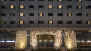 A modern building with a stone archway entrance, multiple floors, and illuminated windows.