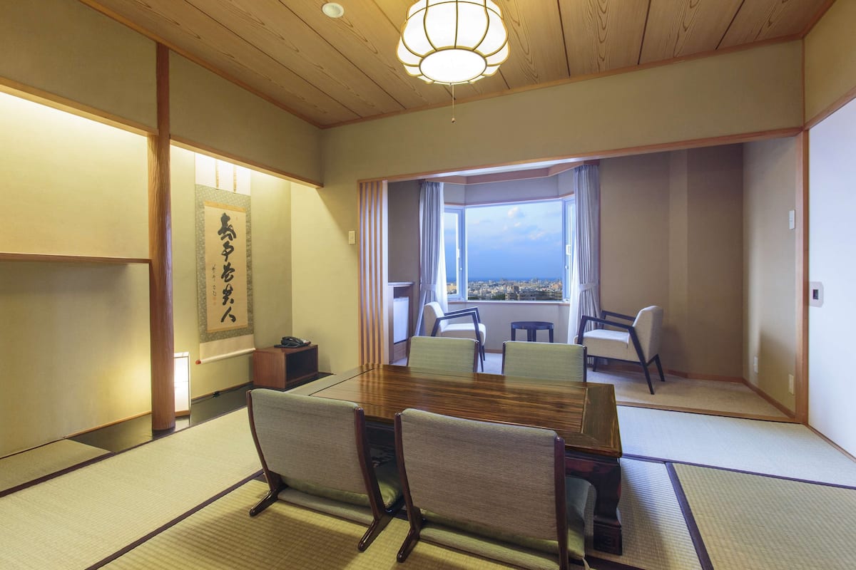 A traditional Japanese room with tatami flooring, a wooden table, and chairs.