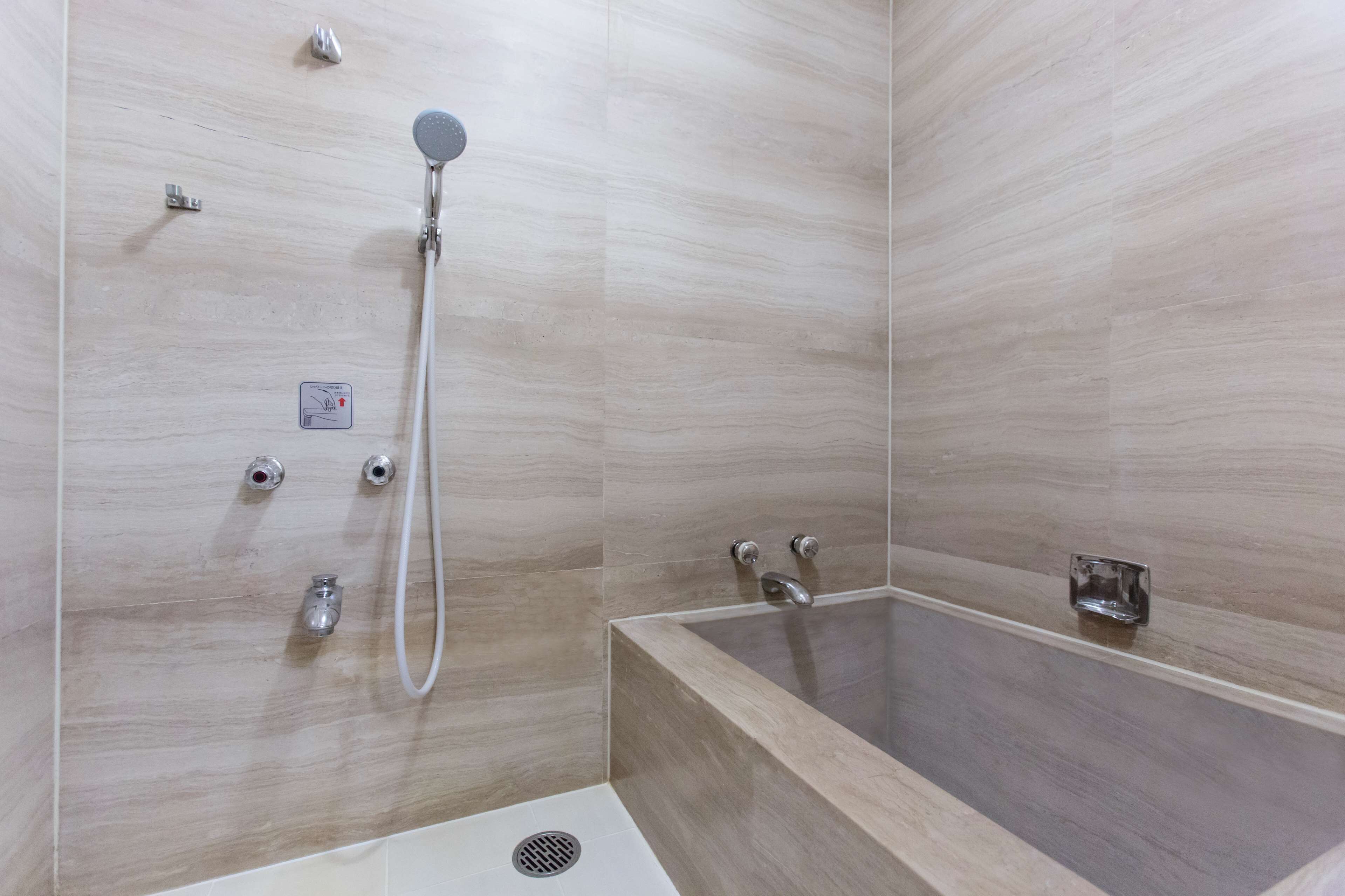 A modern bathroom with a freestanding bathtub, a handheld showerhead, and a wall-mounted faucet.