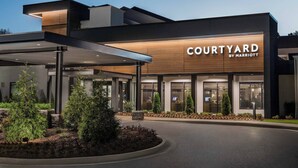 A Courtyard by Marriott hotel entrance with a covered walkway, outdoor seating area, and landscaped garden. - Courtyard by Marriott Atlanta Perimeter Center (Atlanta)