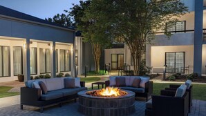 A circular outdoor seating area with a fire pit, surrounded by wicker furniture and a well-maintained lawn. - Courtyard by Marriott Atlanta Perimeter Center (Atlanta)