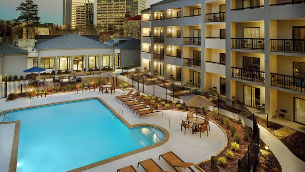 A hotel with a large outdoor swimming pool, sun loungers, and a well-lit courtyard. - Courtyard by Marriott Atlanta Perimeter Center (Atlanta)