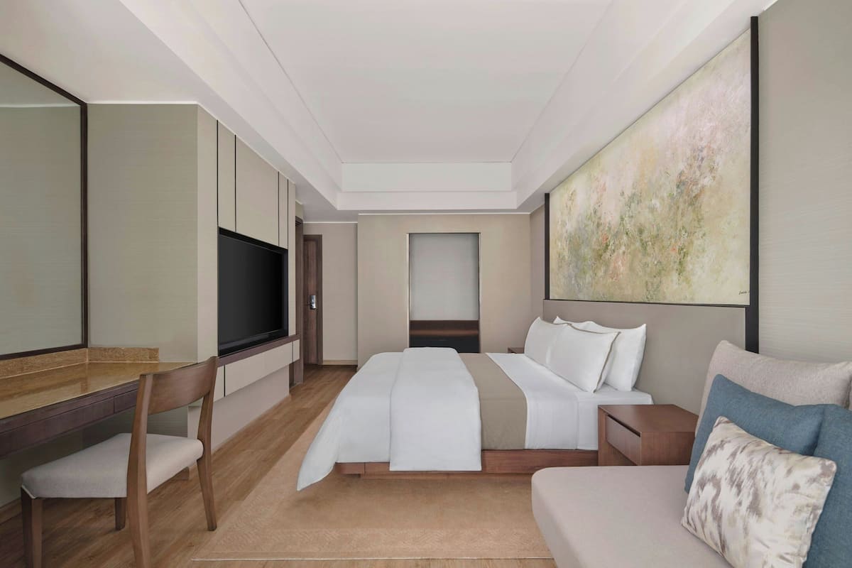Ett modernt hotellrum med en säng, en soffa, ett skrivbord och en tv.