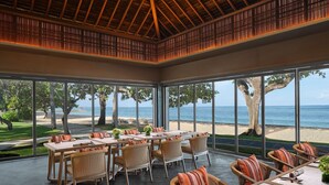 A spacious dining area with large windows overlooking a beach and ocean, featuring wicker furniture and a modern ceiling design. - The Westin Resort Nusa Dua, Bali (Nusa Dua)