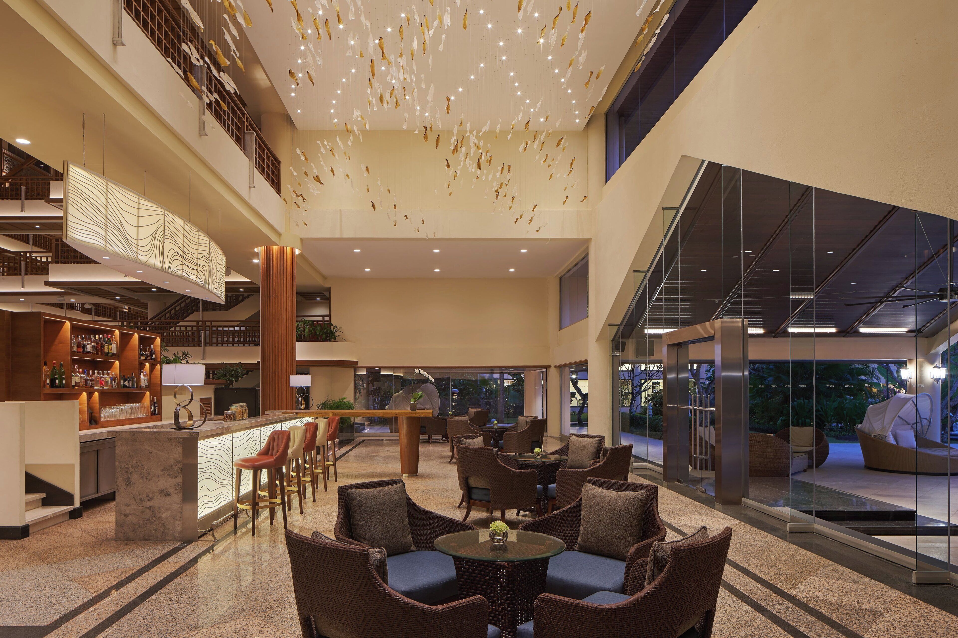 A spacious lobby with a bar area, seating, and a staircase leading to an upper level.