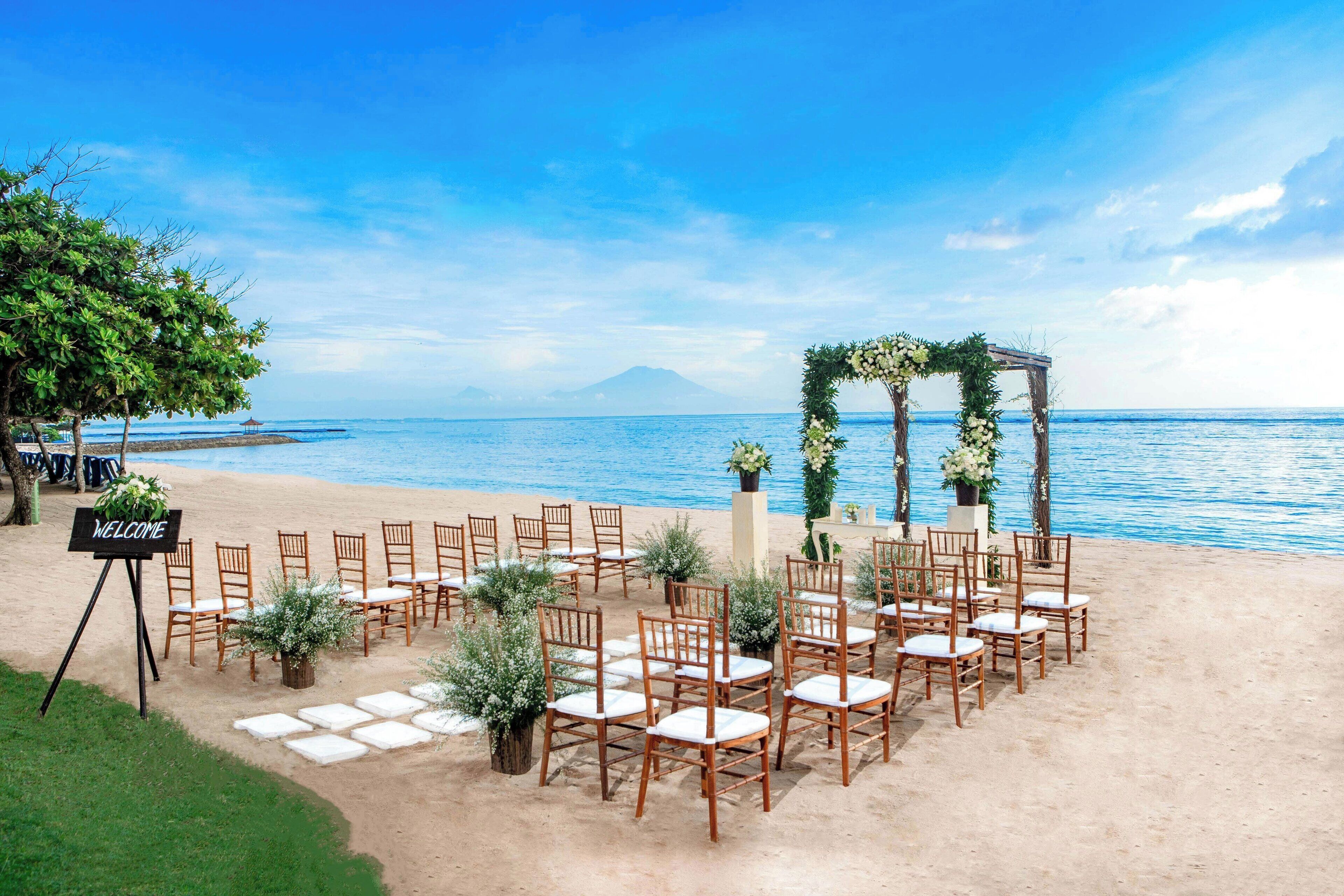 Decoración para boda en la playa, con sillas de madera y un cartel de bienvenida.