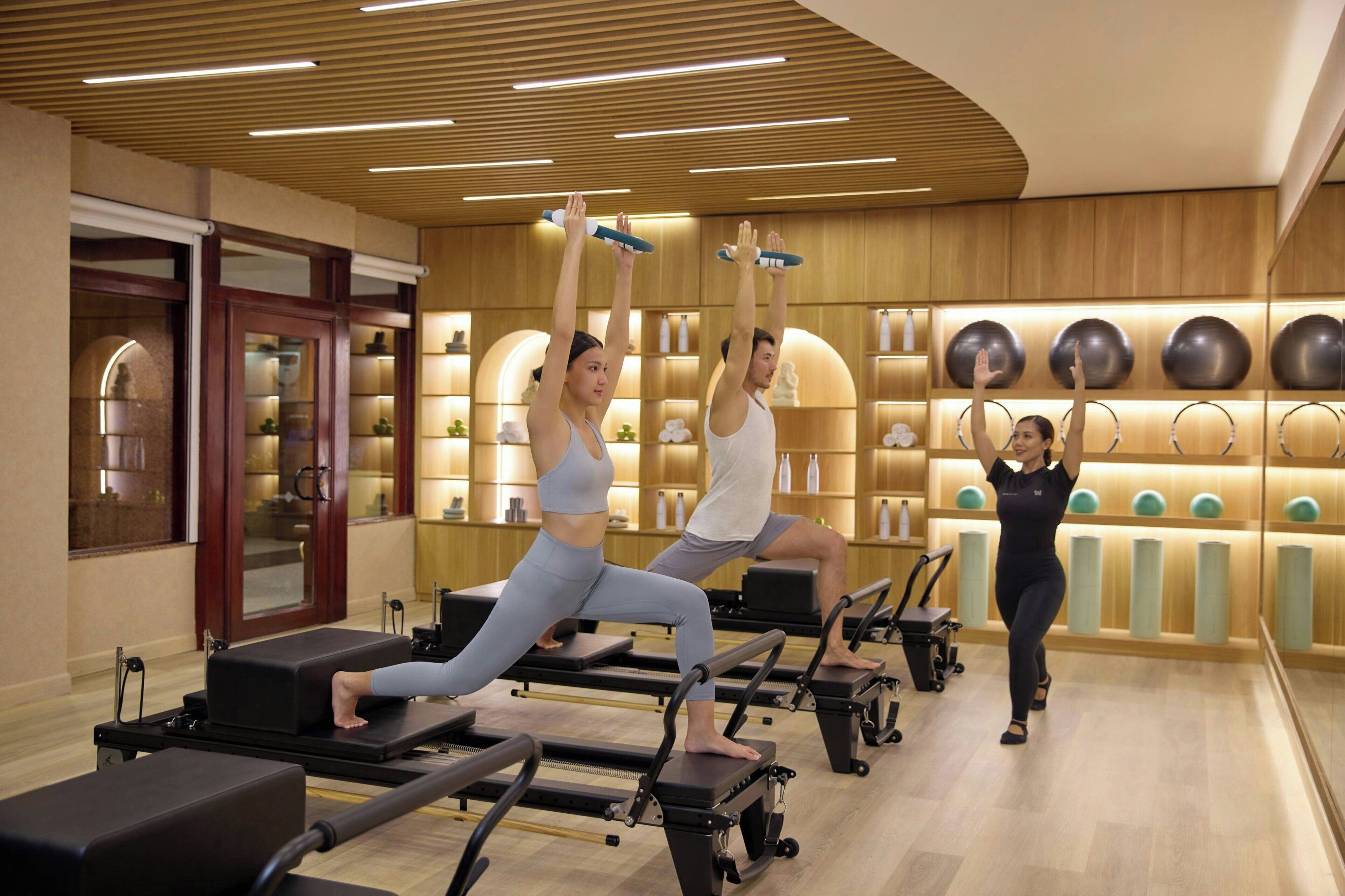 Een Pilates studio met apparatuur, houten wanden en trainingsballen.