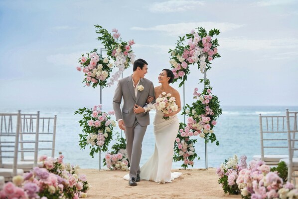 Ceremonia de boda en la playa, con arcos florales y sillas.
