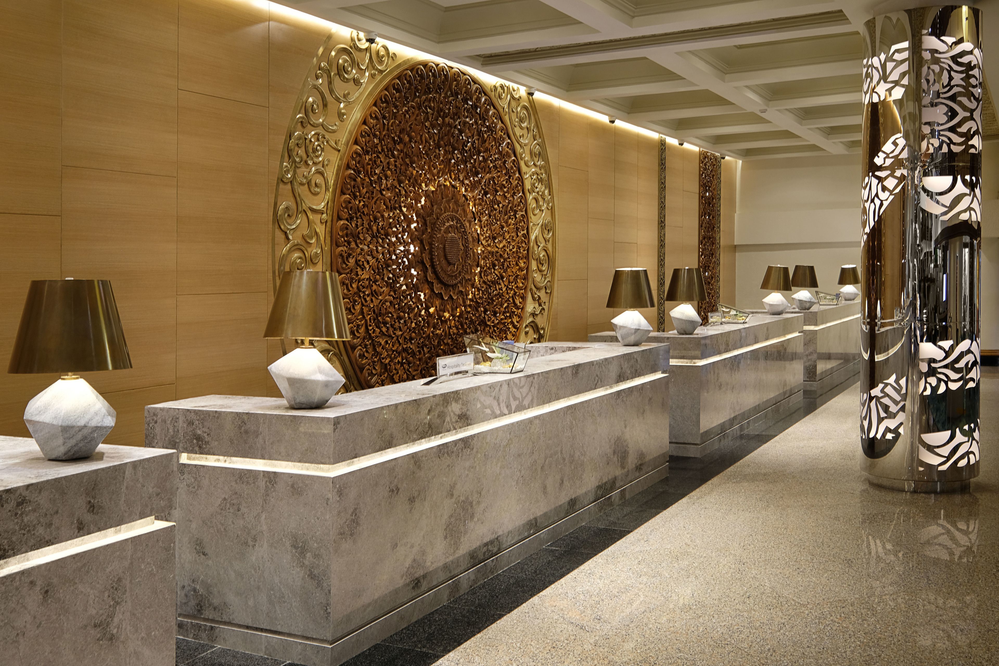 A reception area with marble counters, a large decorative wall, and patterned columns.