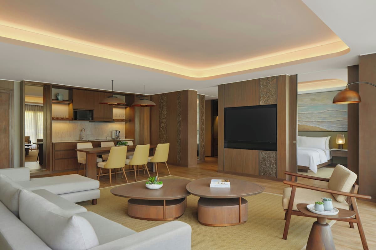 Ett modernt hotellrum med ett vardagsrumsutrymme, en matplats och ett sovrum med en stor TV och bekväma sittmöbler.