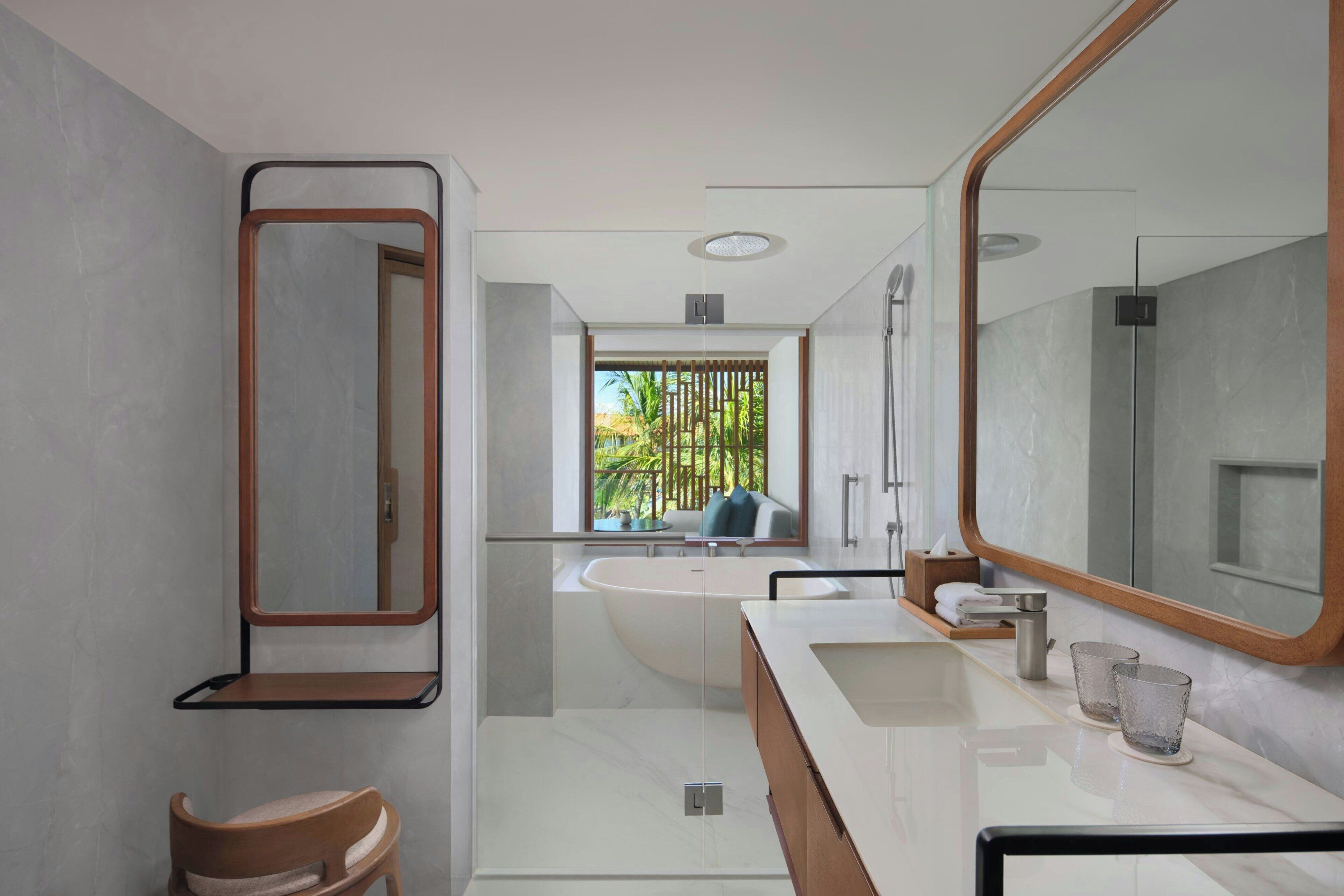 Un bagno moderno con uno specchio grande, una vasca, un mobile lavabo e una sedia.