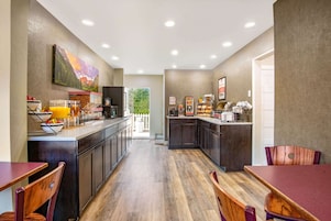 Una cocina moderna con suelo de madera, una barra desayunadora y un comedor con sillas de madera.