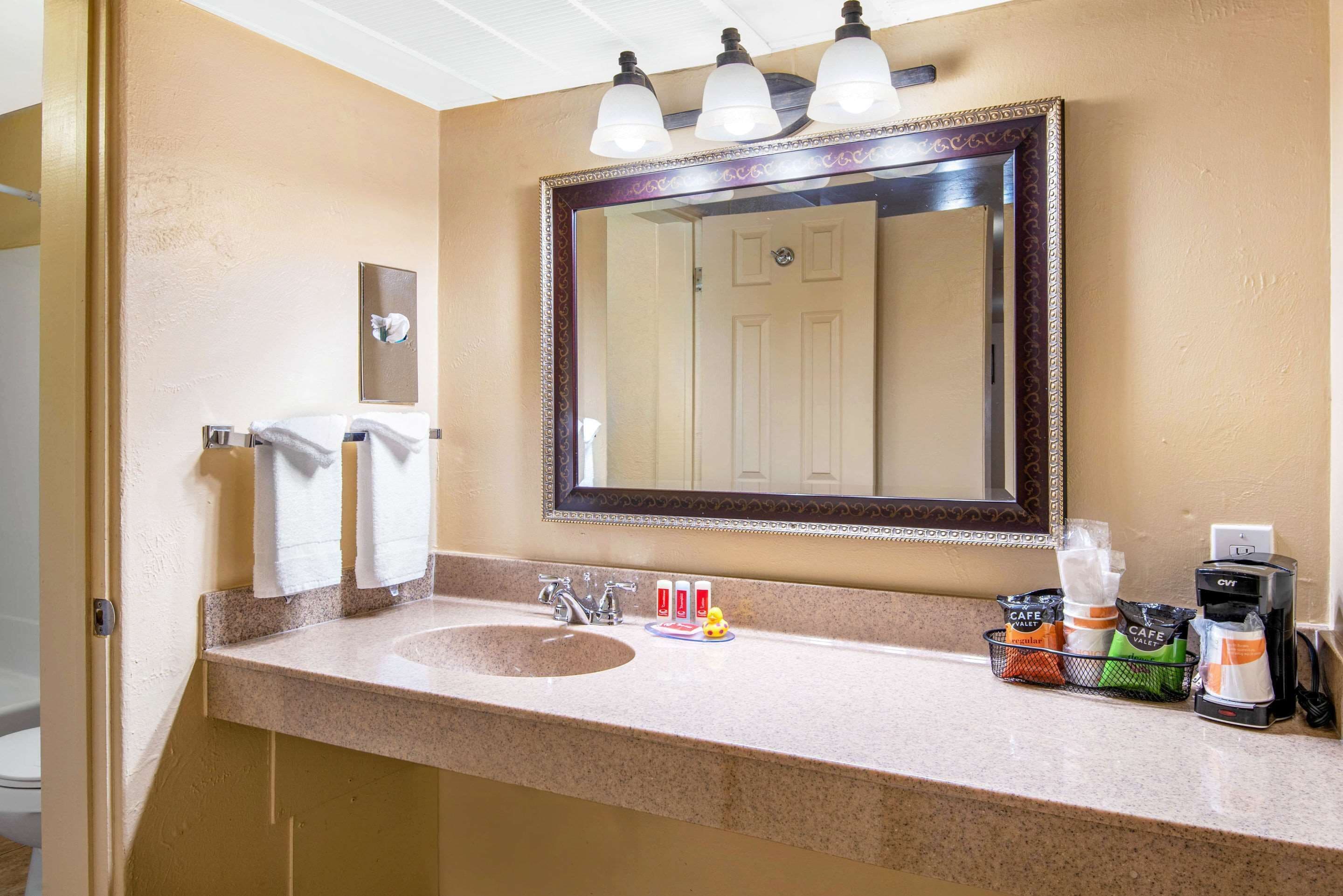 A bathroom with a sink, mirror, and toiletries.