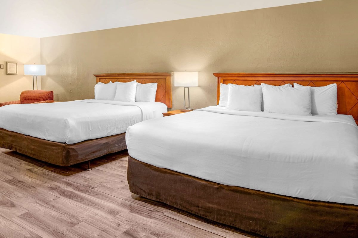 A hotel room with two beds, wooden headboards, and bedside lamps.