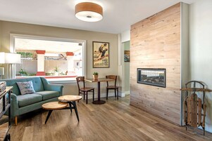 Una sala de estar acogedora con un sofá, dos sillones, una mesa de centro, una pared de madera y una chimenea.