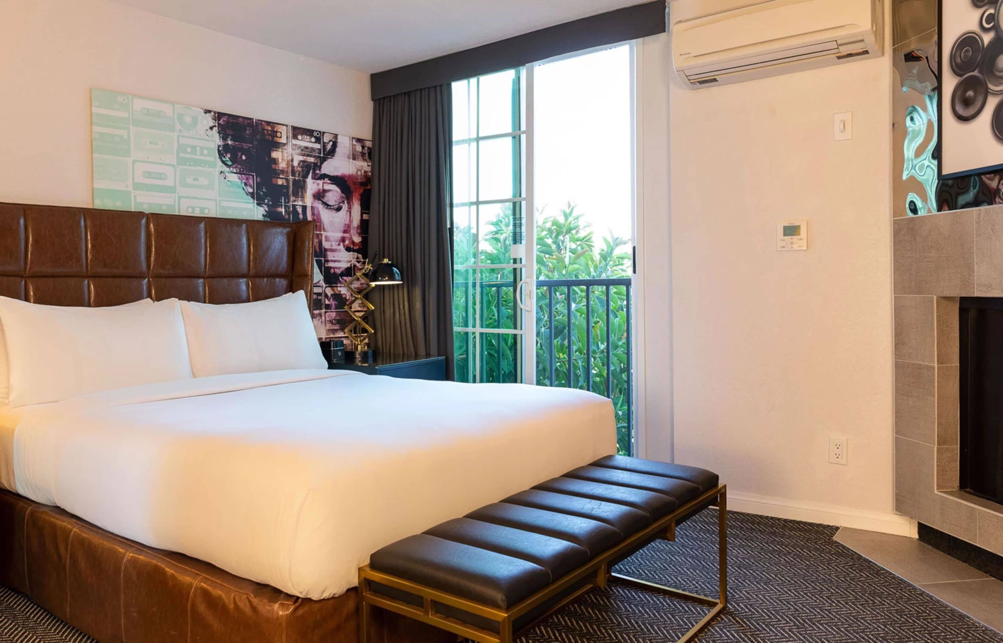 Une chambre d’hôtel avec un grand lit, un banc, une cheminée et un balcon avec vue.