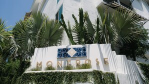 Een gebouw met een bord waarop 'MONROSE' staat, omringd door palmbomen en cactussen.