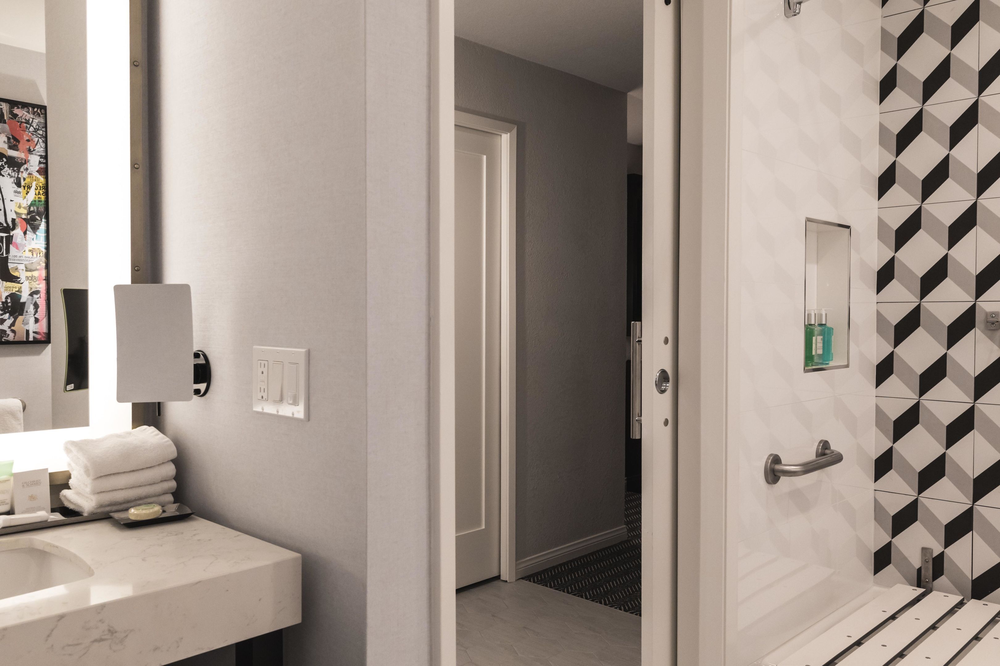 Ein Badezimmer mit Waschbecken, Handtuchhalter und Dusche mit geometrischem Fliesenmuster.