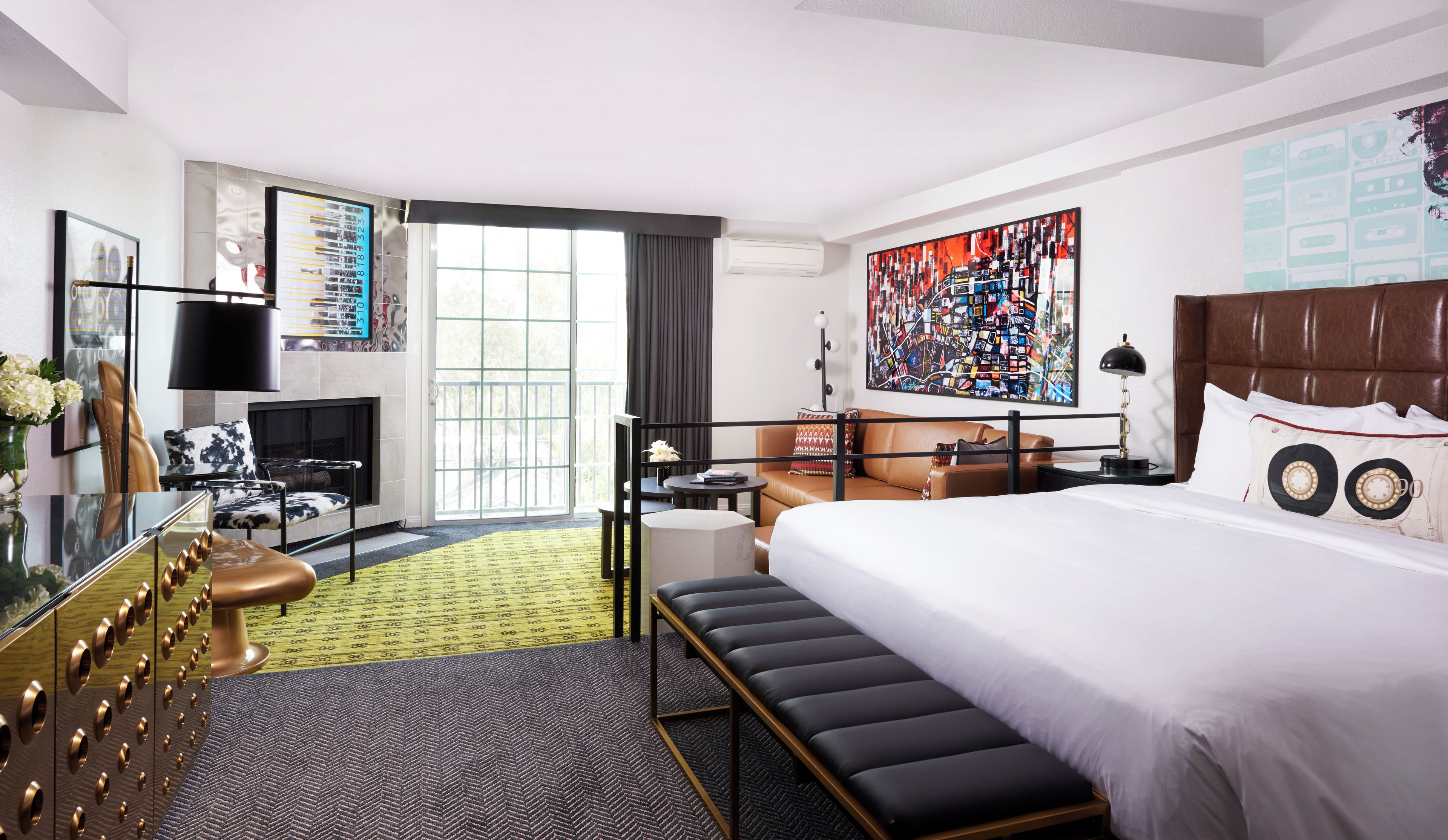 Une chambre d’hôtel avec un grand lit, un bureau, une chaise, un canapé, une télévision et un tableau au mur.