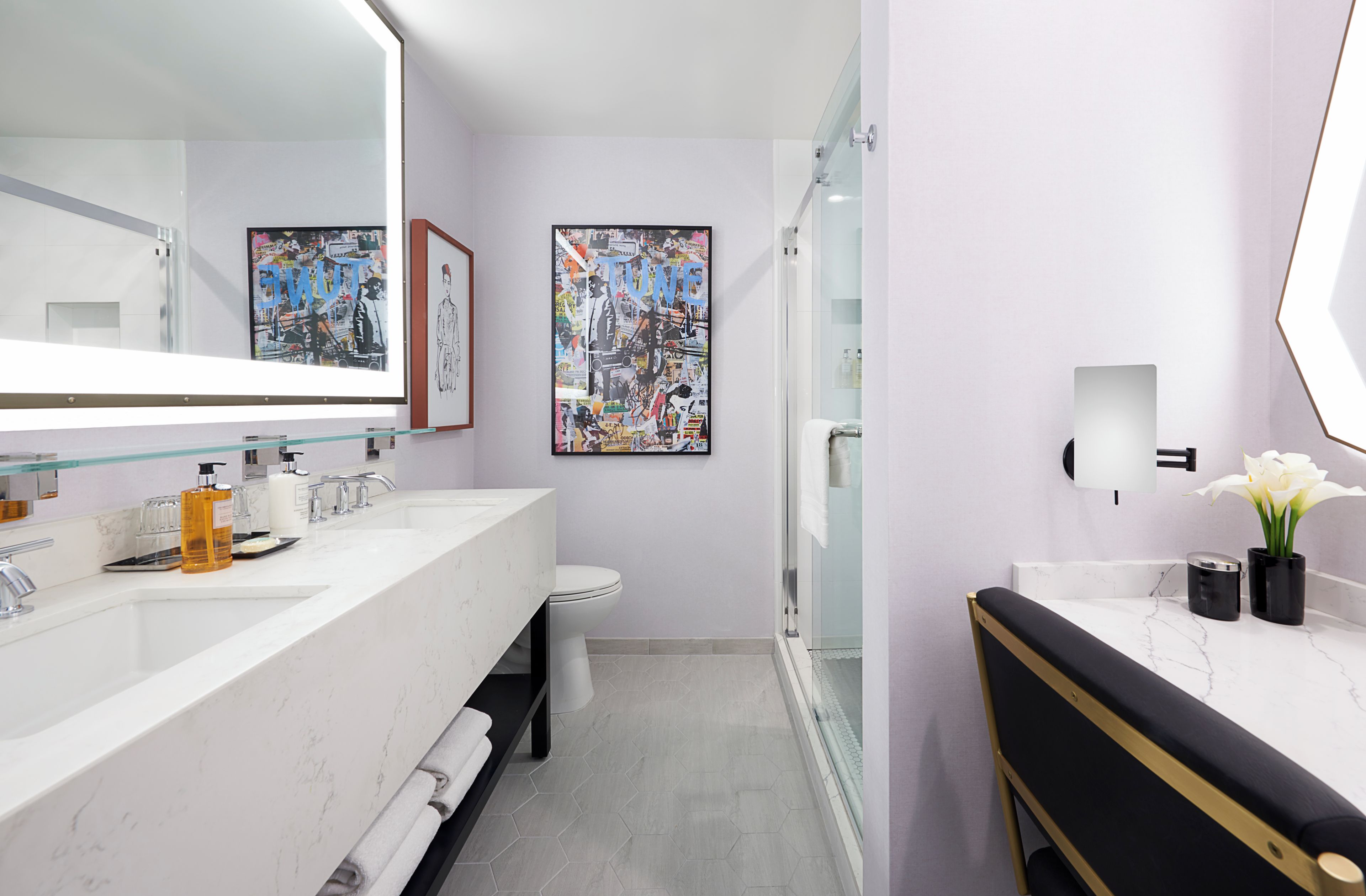 Un bany modern amb plat de dutxa de vidre, un vàter blanc i un lavabo amb taulell de marbre.