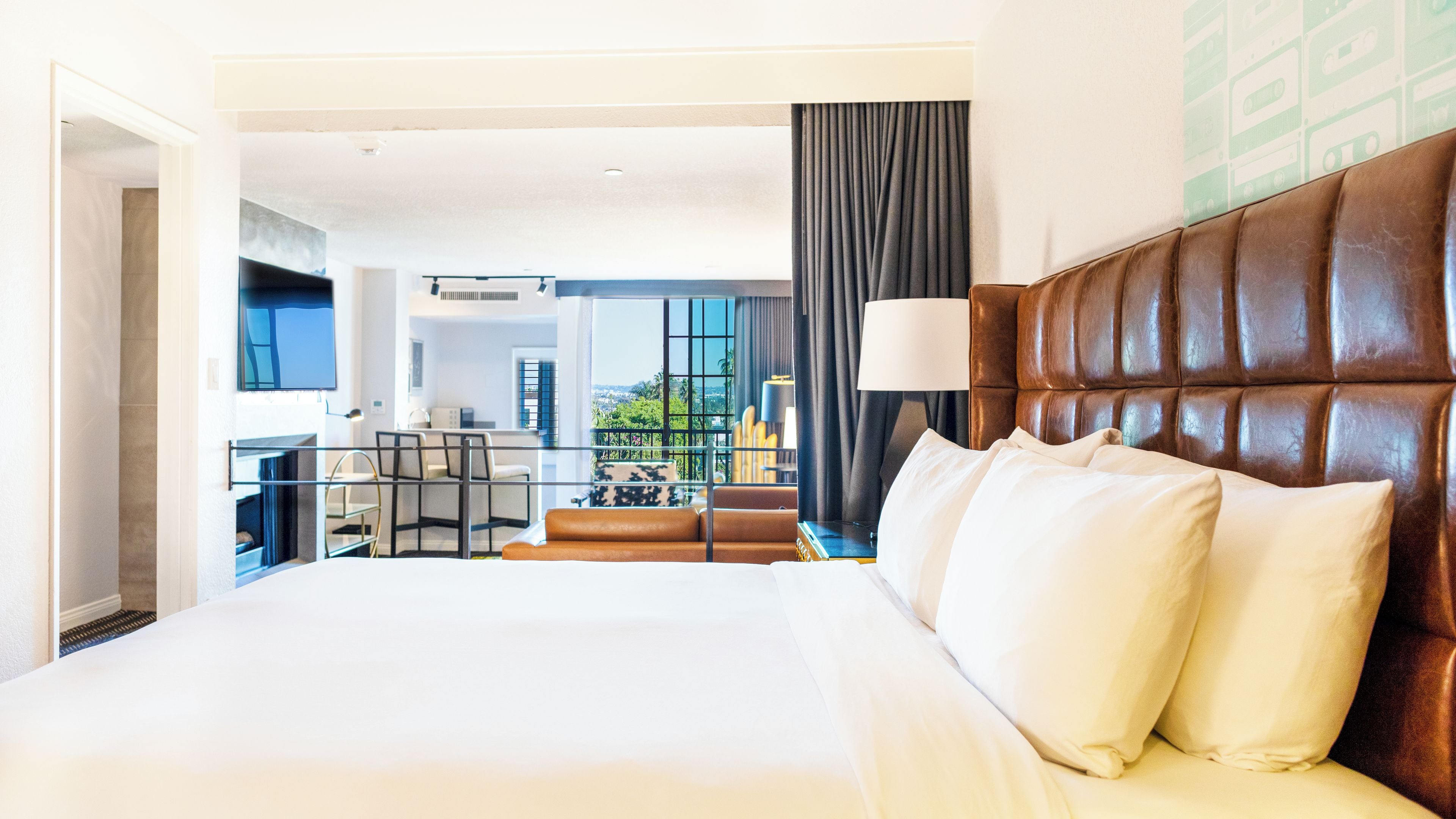 Ein Hotelzimmer mit einem großen Bett, Stadtblick, einem Balkon und einer Essecke.