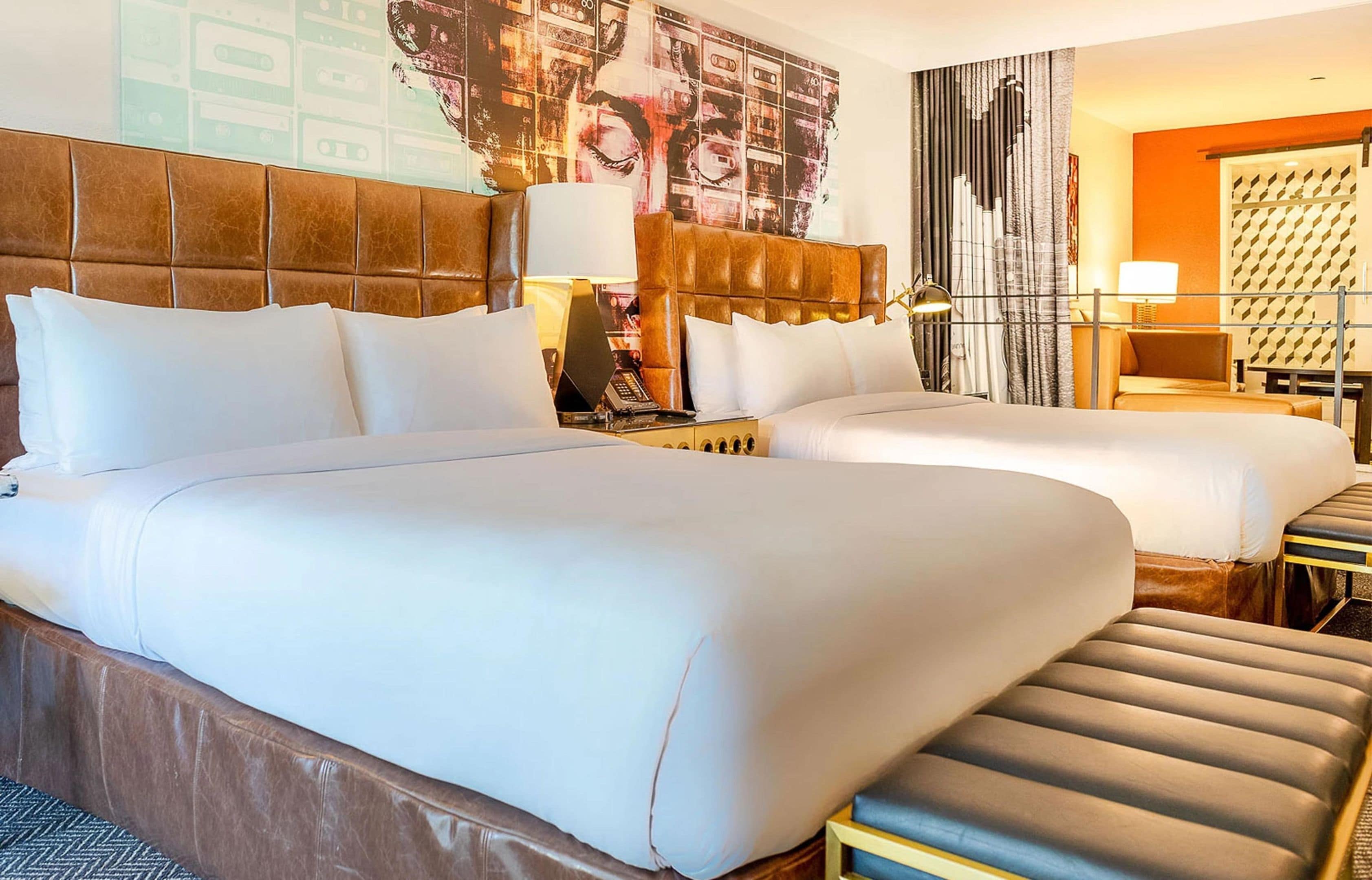 Une chambre d’hôtel avec deux lits, un canapé, un bureau et une grande œuvre d’art abstraite accrochée au mur.